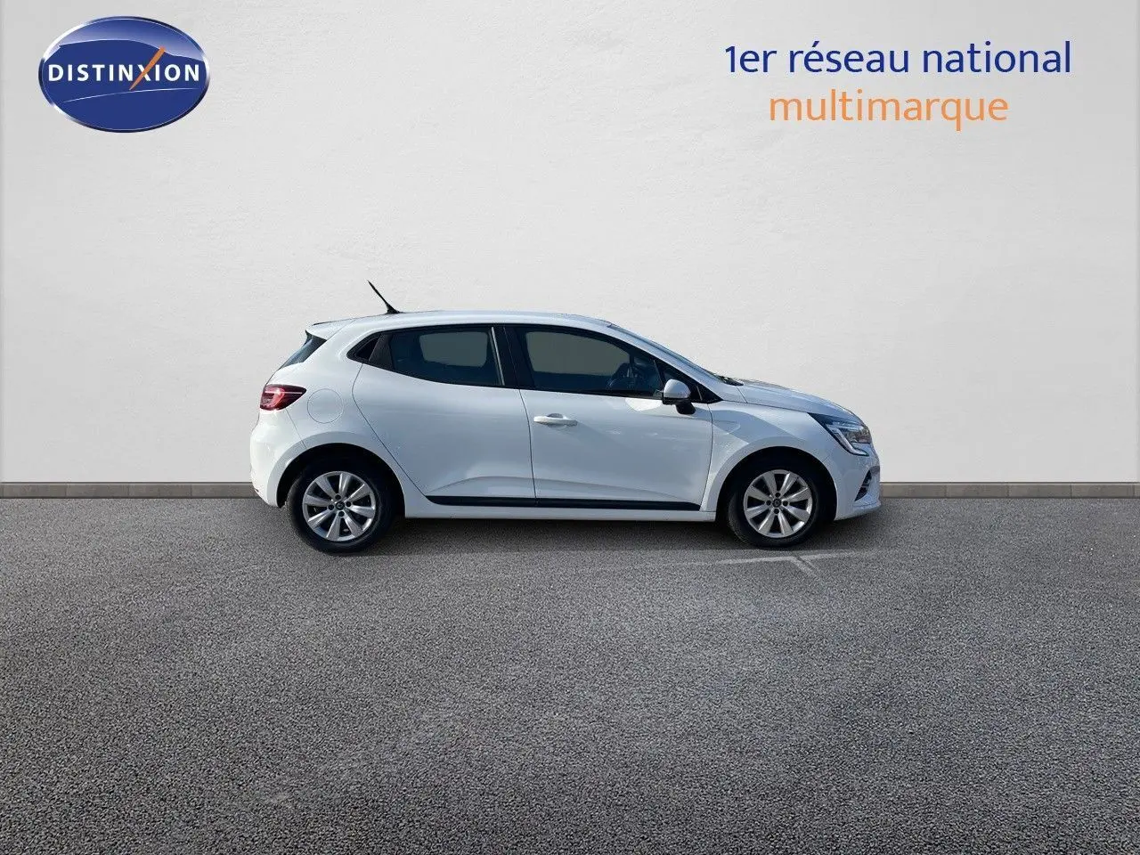 Profil droit d'une Renault Clio Société blanche Glacier de 2020, garée devant un mur blanc avec logo Distinxion.