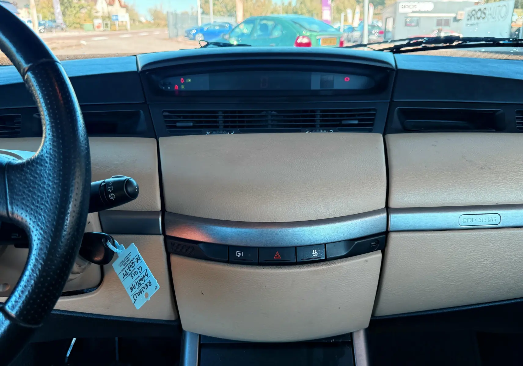 Tableau de bord beige et noir vu de face dans une Renault Avantime gris, avec volant à gauche et commandes centrales visibles.