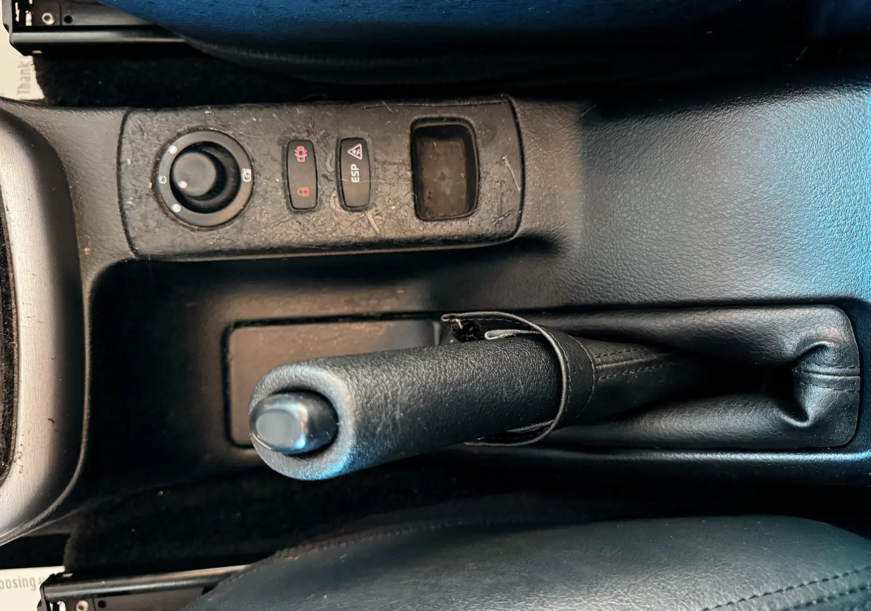 Vue rapprochée de la poignée de frein à main en cuir noir et des commandes de la console centrale d'une Renault Avantime gris.