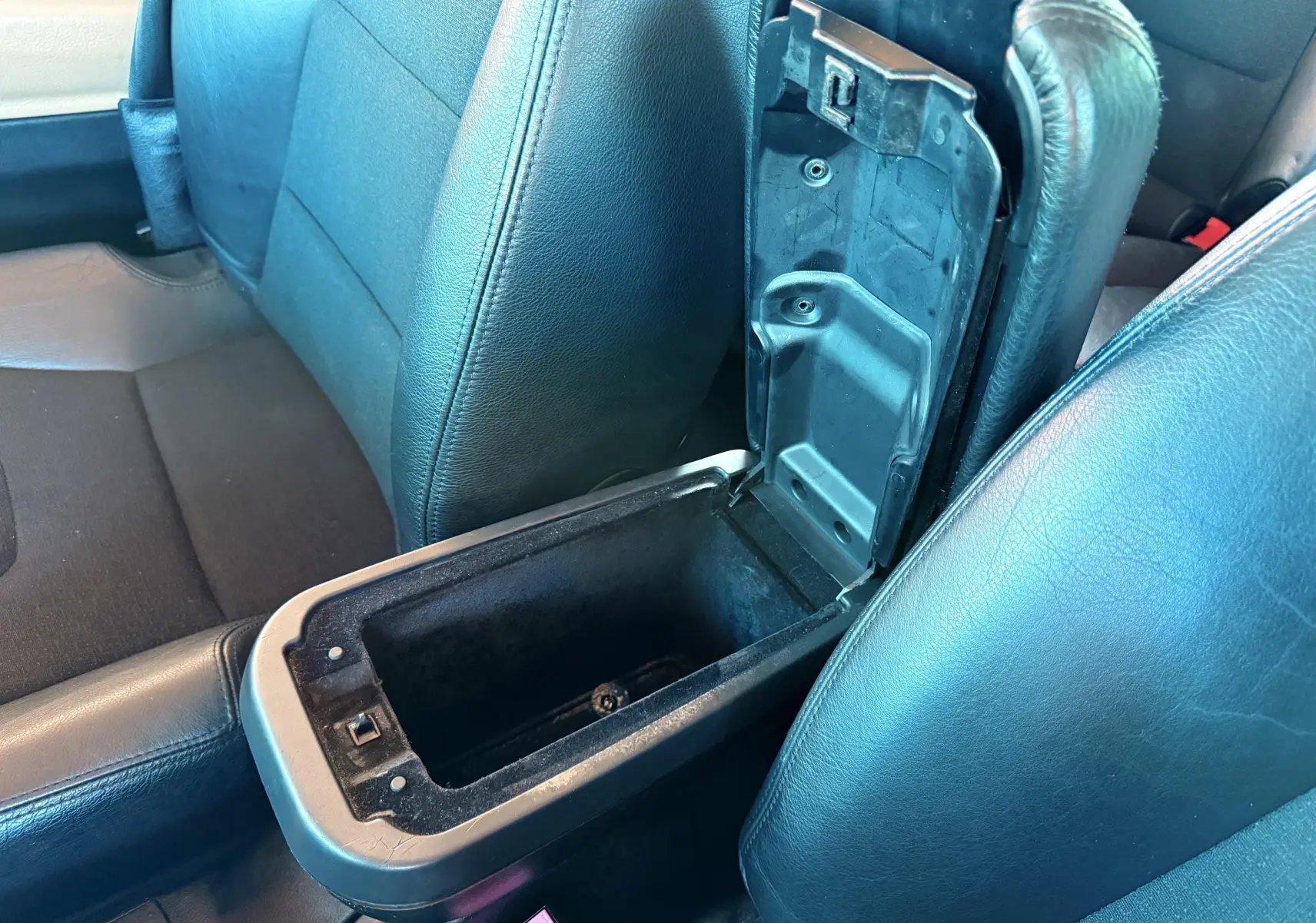 Gros plan sur la console centrale ouverte entre les sièges avant en cuir noir du Renault Avantime gris de 2002.