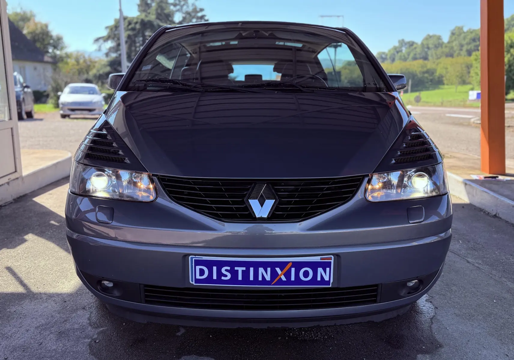 Vue frontale d'une Renault Avantime gris métallisé avec phares allumés et plaque Distinxion visible.