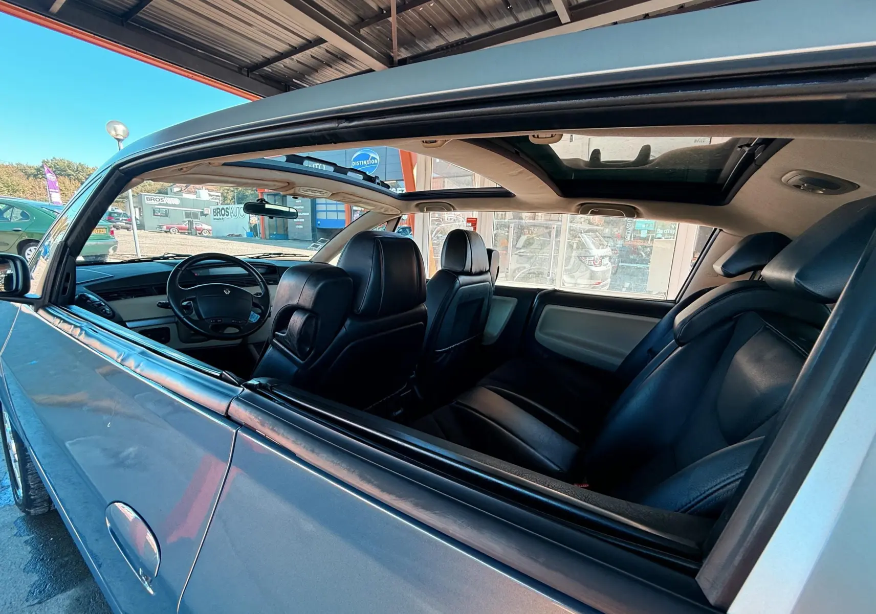 Intérieur noir cuir de la Renault Avantime gris, vue côté gauche avec toit panoramique ouvert.