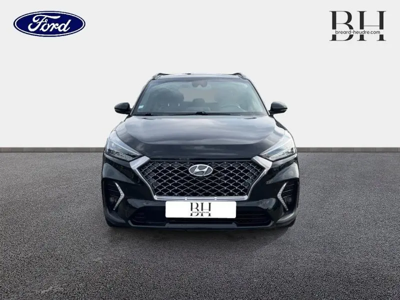 Vue frontale d'un Hyundai Tucson 2020 Phantom Black Métal avec calandre chromée et feux LED allumés.