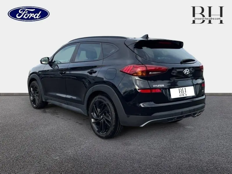 Vue 3/4 arrière droite du Hyundai Tucson Phantom Black Métal avec jantes noires et feux arrière LED visibles.