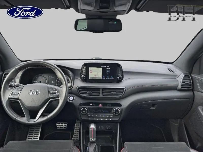 Intérieur moderne du Hyundai Tucson 1.6 CRDI Phantom Black, vue frontale du tableau de bord avec écran tactile et volant multifonction.