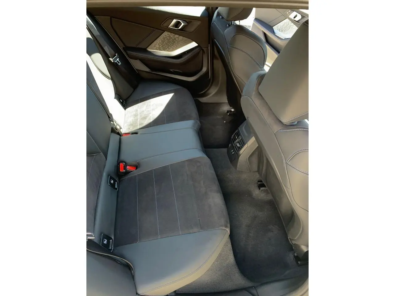 Vue intérieure côté droit des sièges arrière en Alcantara noir et cuir avec surpiqûres bleues dans une BMW Série 1 M Sport 2025.
