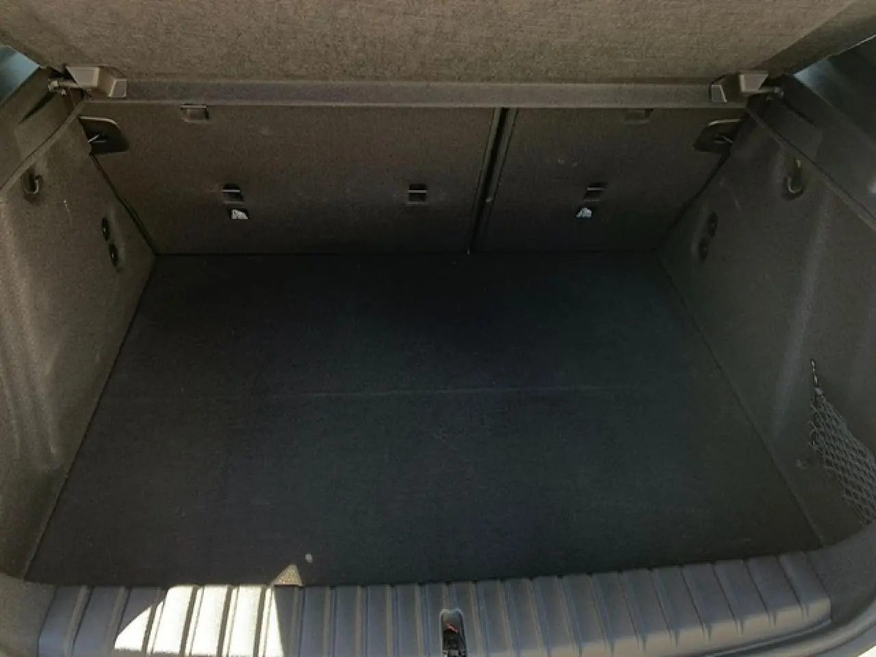 Coffre spacieux de BMW Série 1 118d M Sport noir métal, avec filet côté droit et crochets porte-sacs visibles.