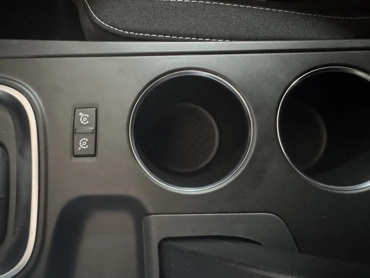Gros plan sur la console centrale noire avec porte-gobelets et commandes du régulateur de vitesse de la Renault Mégane Business.