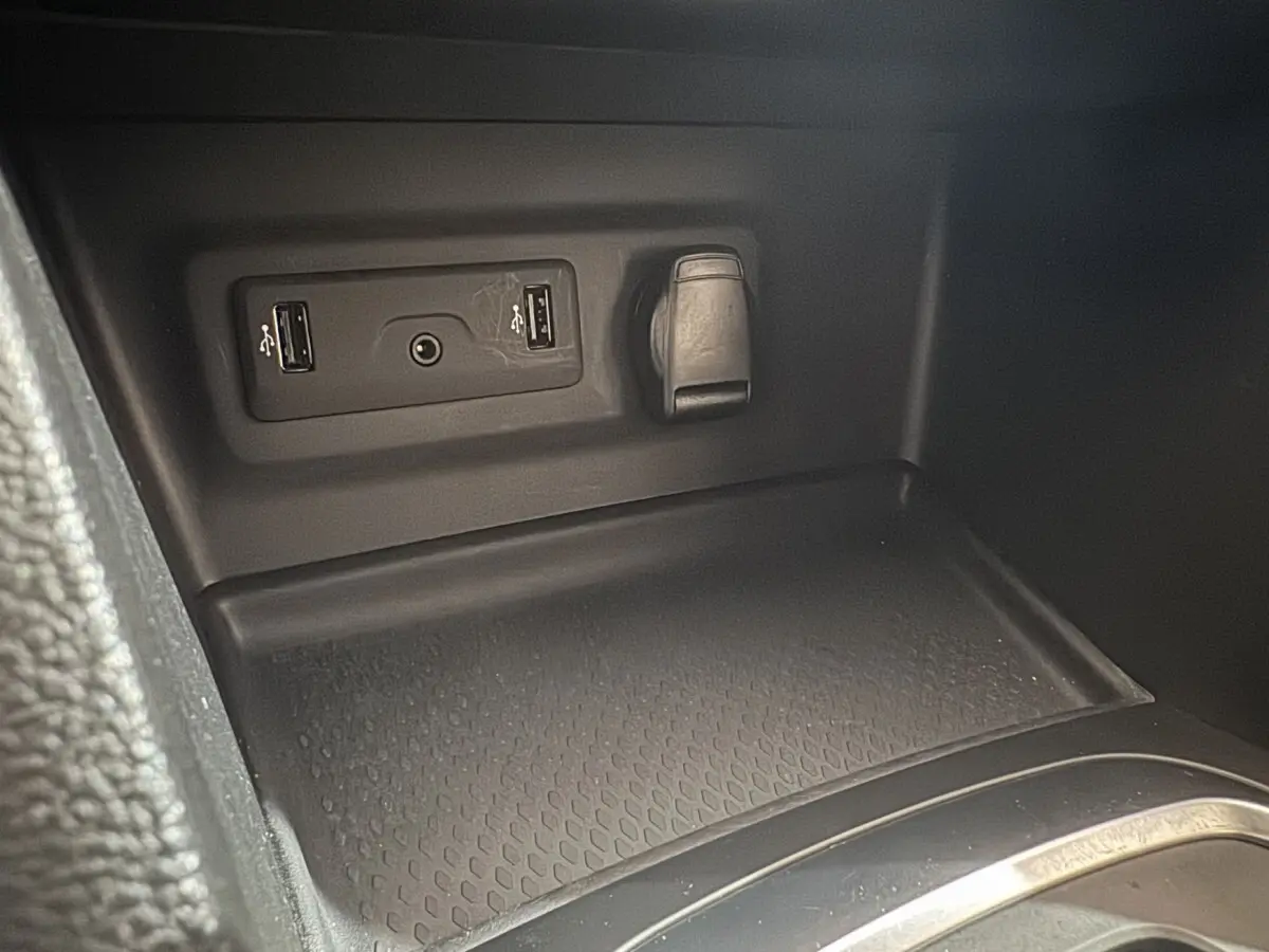 Gros plan sur la console centrale intérieure de la Renault Mégane Business gris clair, montrant prises USB et prise 12V.