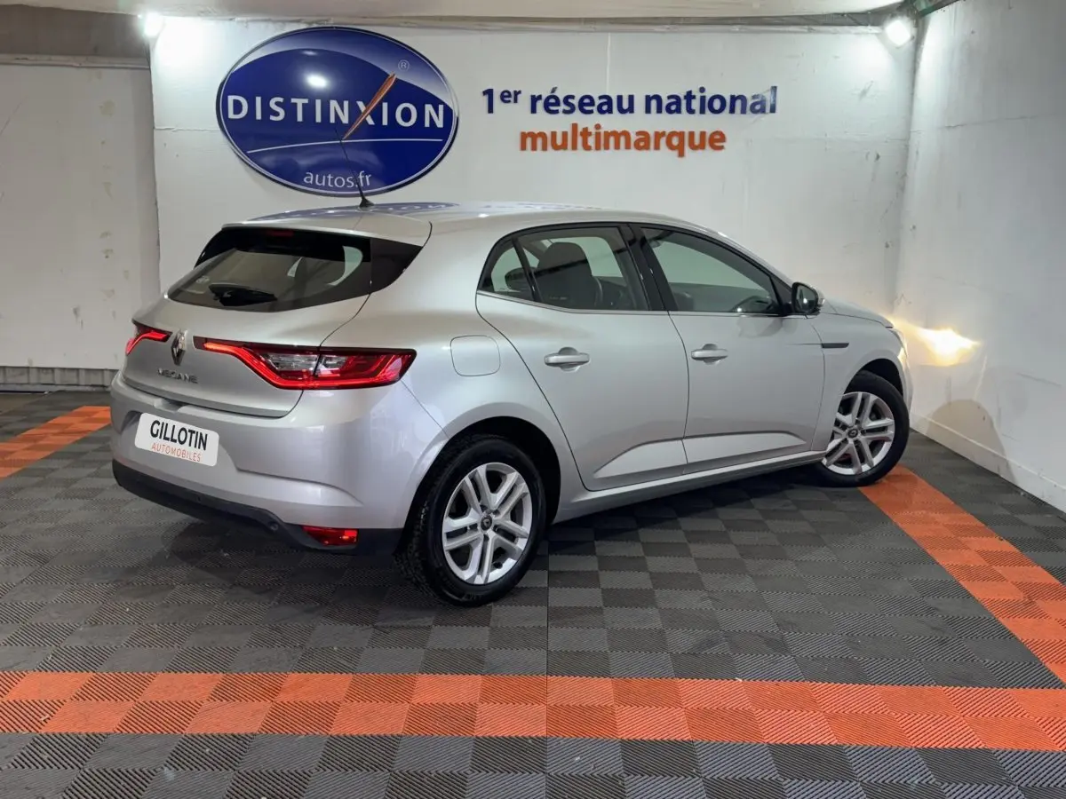 Renault Mégane Business gris clair vue 3/4 arrière droit dans un showroom avec éclairage mural.