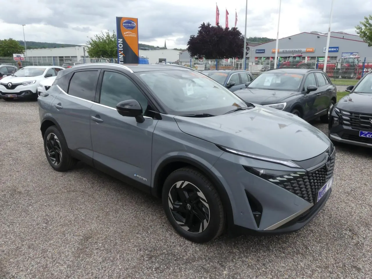 Nissan Qashqai 1.5 e-Power gris métallisé en 3/4 avant droit avec toit noir et jantes noires distinctives.