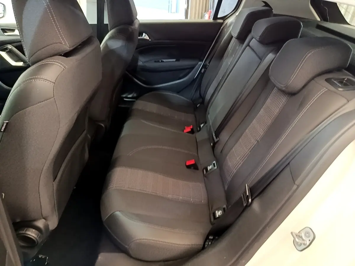Vue intérieure côté droit sur la banquette arrière noire de la Peugeot 308 blanche, avec appuie-têtes et ceintures visibles.