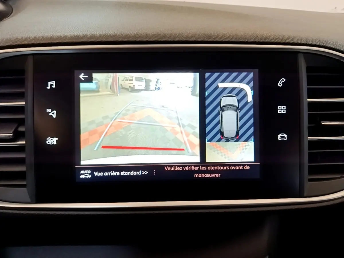 Écran tactile central de la Peugeot 308 blanc montrant la caméra de recul et l’aide au stationnement arrière.