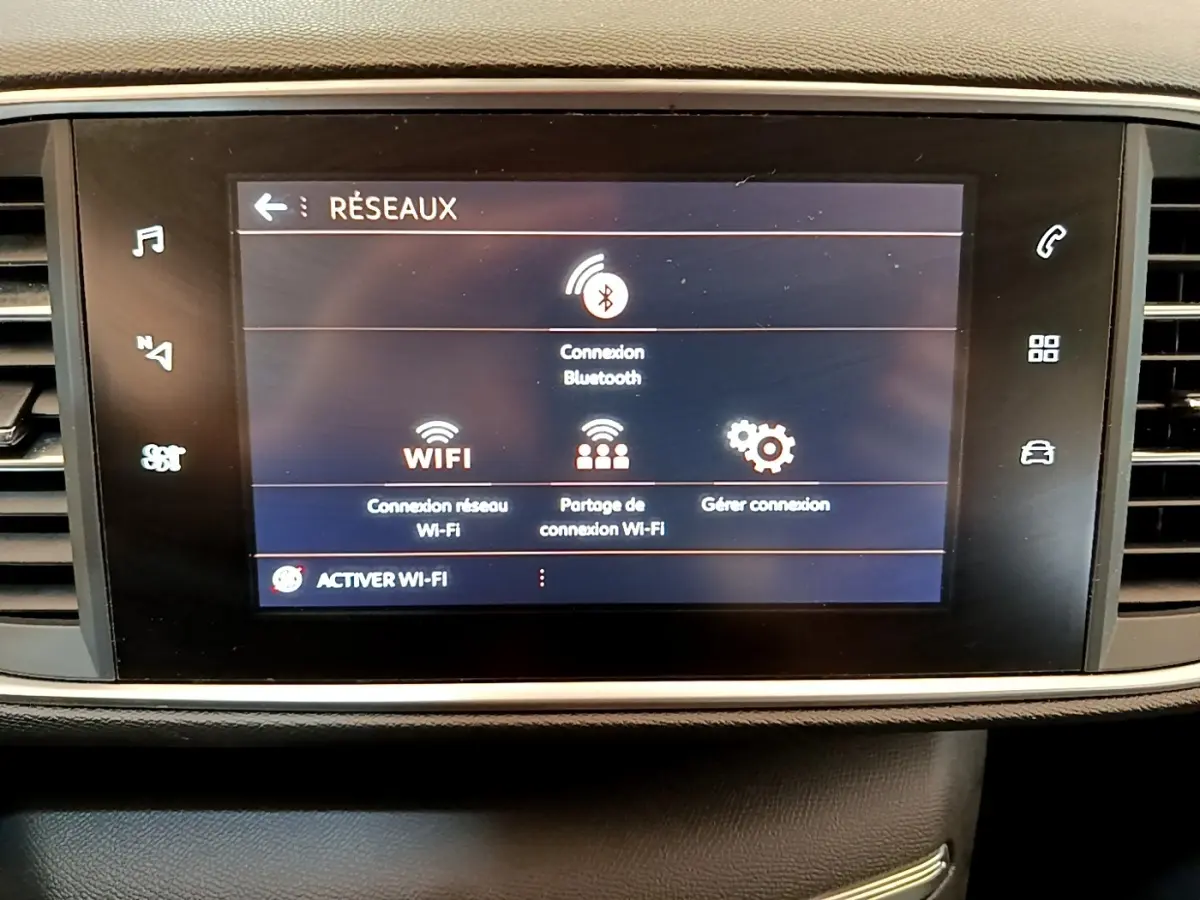 Écran tactile central affichant les options réseau Bluetooth et Wi-Fi dans l'habitacle d'une Peugeot 308 blanche.