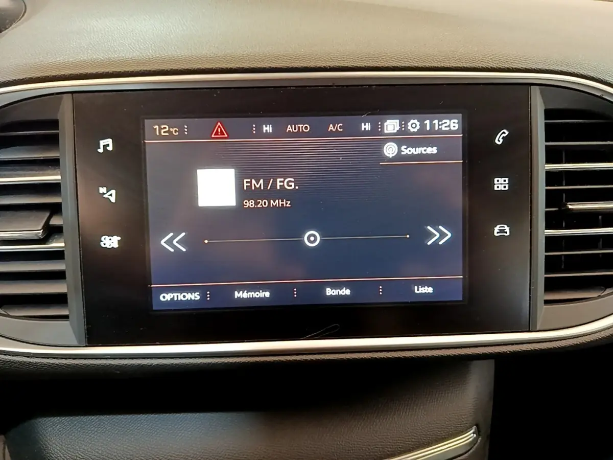 Écran tactile central de la Peugeot 308 blanc 2017 affichant la radio FM à 98,20 MHz, entouré de commandes.