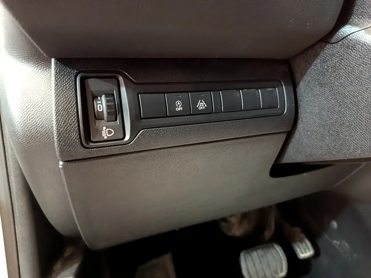 Vue intérieure côté conducteur du tableau de bord noir avec commandes d'éclairage et aides à la conduite sur Peugeot 308 blanc.
