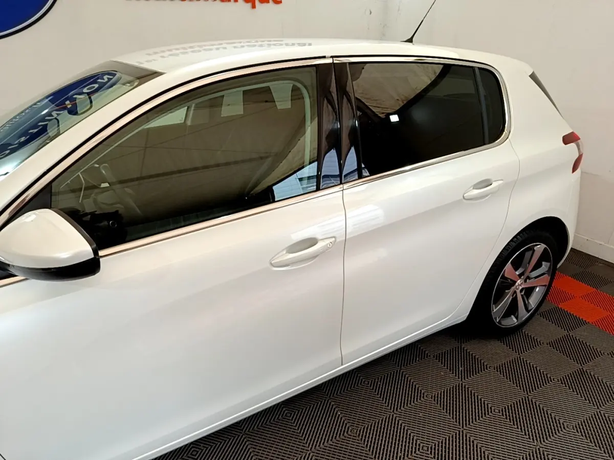 Vue latérale côté gauche d'une Peugeot 308 blanche de 2017, avec vitres teintées et jantes alliage distinctives.
