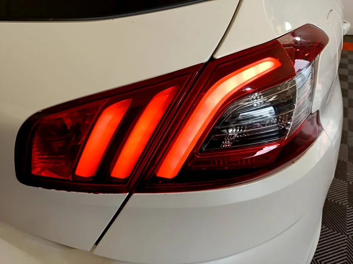 Gros plan sur le feu arrière droit rouge allumé d'une Peugeot 308 blanche, mettant en valeur ses trois griffes lumineuses.