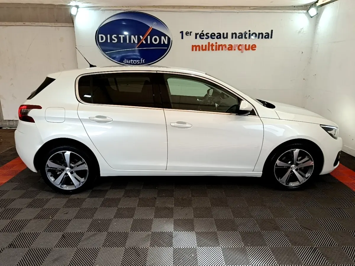 Profil droit d'une Peugeot 308 blanche 2017 dans un showroom avec sol damier et logo Distinxion en arrière-plan.