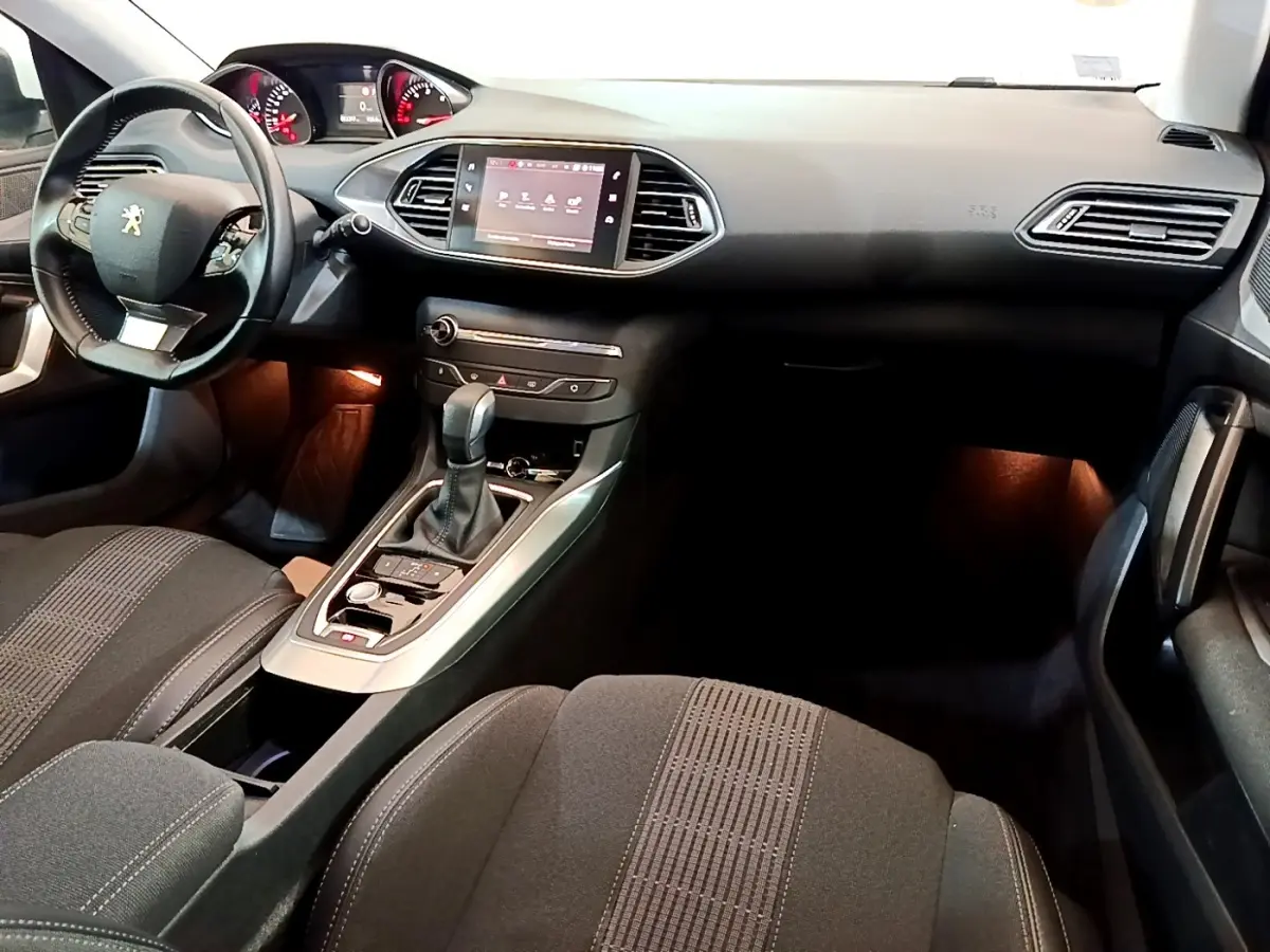 Vue intérieure avant droite du Peugeot 308 blanc 2017, avec tableau de bord moderne et écran tactile central.