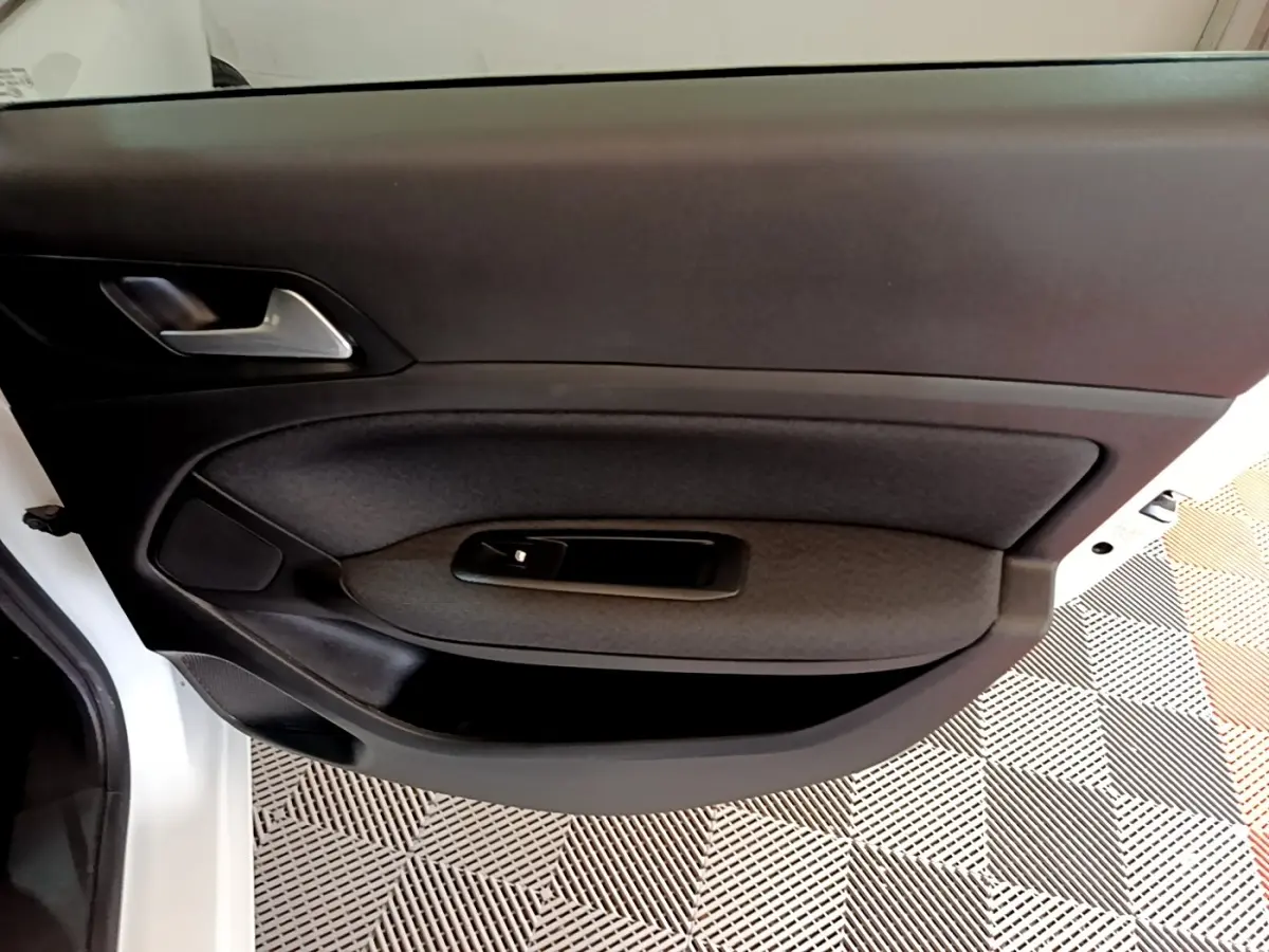 Vue rapprochée de la porte avant gauche blanche de la Peugeot 308 avec garniture noire et poignée argentée.