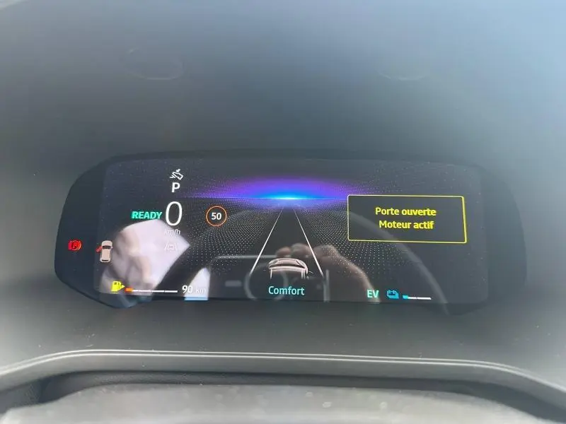 Tableau de bord numérique du Renault Captur 1.8 E-Tech hybride, affichant vitesse zéro et alerte porte ouverte.