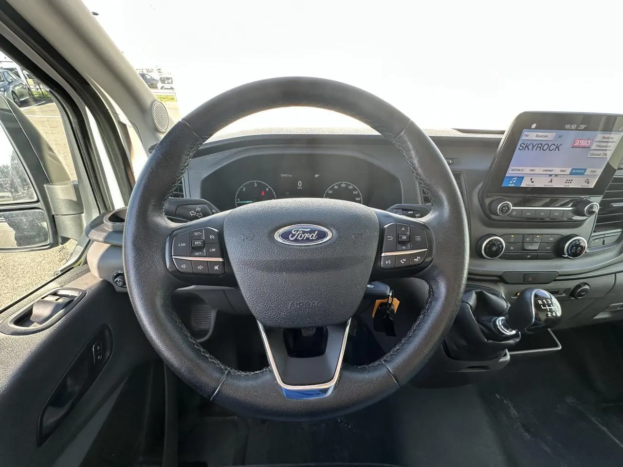 Vue intérieure centrée sur le volant cuir Ford et la console centrale avec écran tactile du Ford Transit Fourgon blanc 2020.