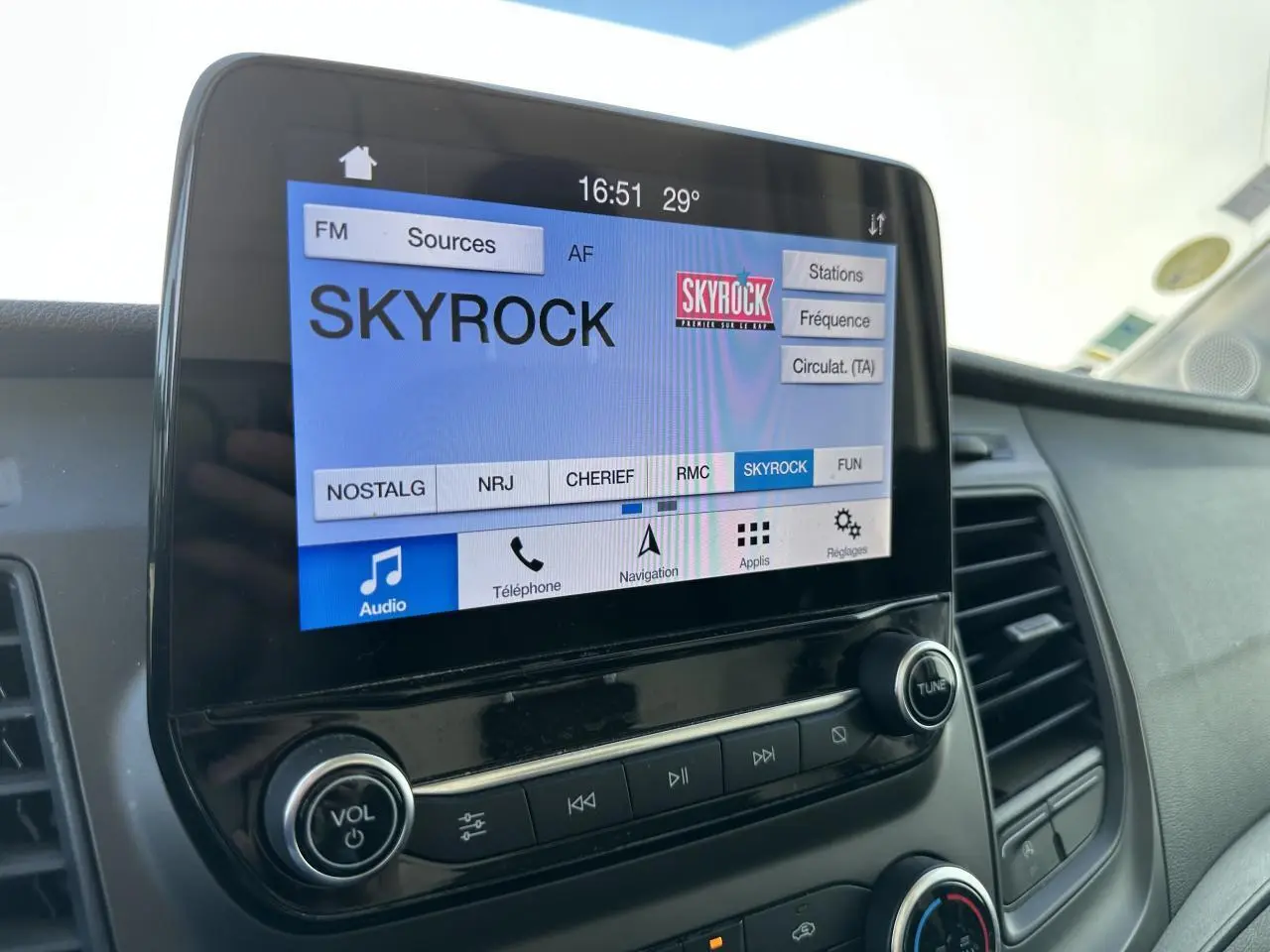 Écran tactile du système audio SYNC 3 du Ford Transit Fourgon blanc, affichant la radio Skyrock.