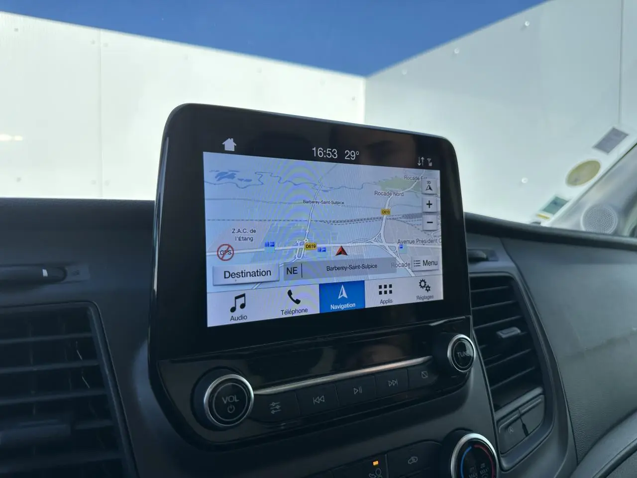 Écran tactile central du Ford Transit Fourgon blanc 2020 affichant la navigation GPS, entouré de commandes audio et climatisation.