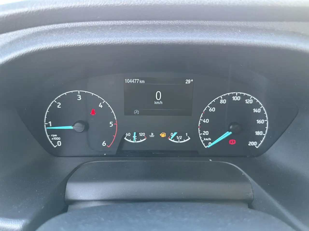 Vue rapprochée du tableau de bord du Ford Transit Fourgon blanc, affichant le compteur et l'ordinateur de bord à l'arrêt.