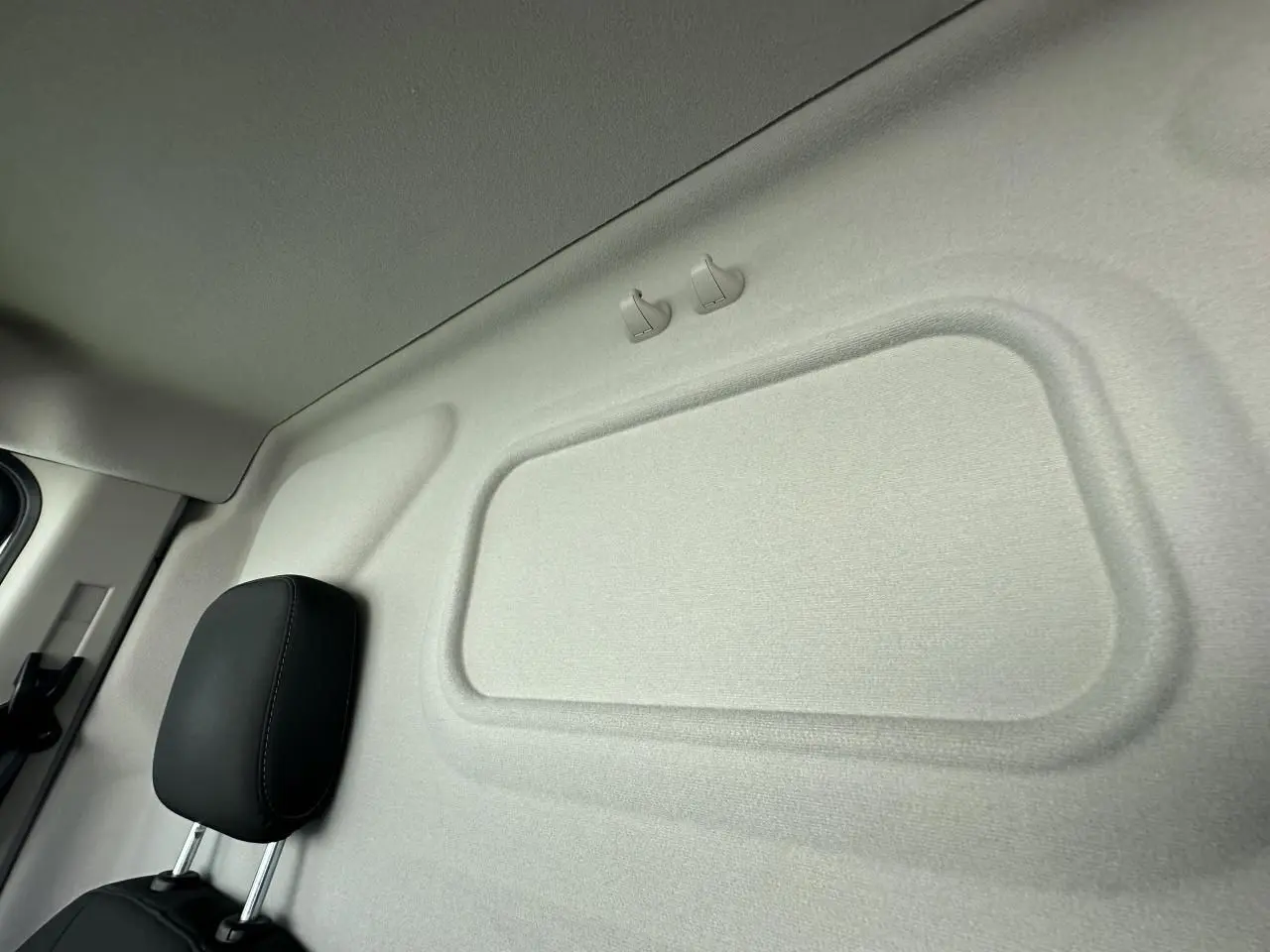Détail de la cloison intérieure beige et appuie-tête noir du siège conducteur du Ford Transit Fourgon blanc 2020.