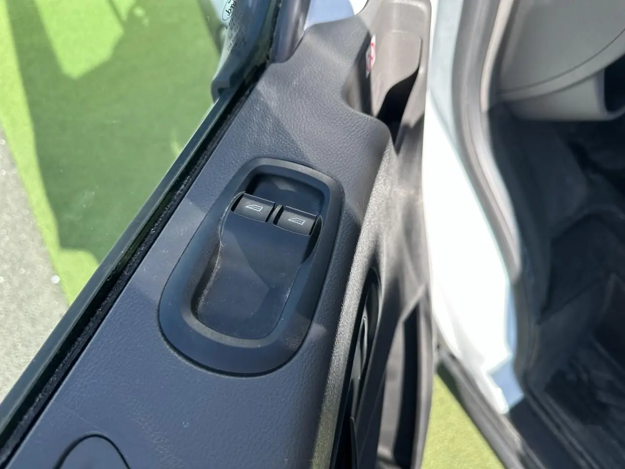 Gros plan sur les commandes de lève-vitres côté conducteur du Ford Transit Fourgon blanc, intérieur noir.