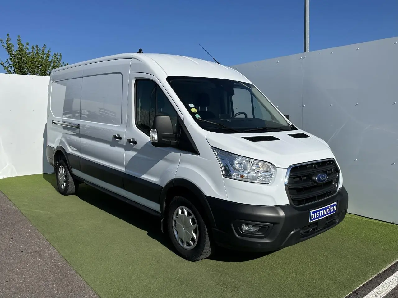 Fourgon Ford Transit blanc en 3/4 avant droit avec calandre noire et pare-chocs avant noir mat.