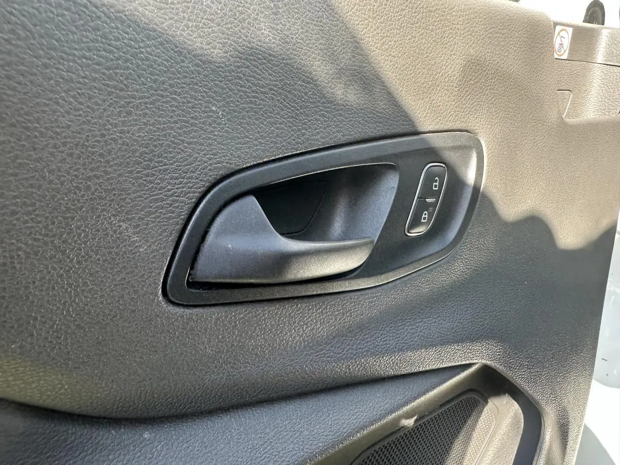 Poignée intérieure de porte côté gauche en plastique noir du Ford Transit Fourgon blanc 2020, avec boutons de verrouillage.