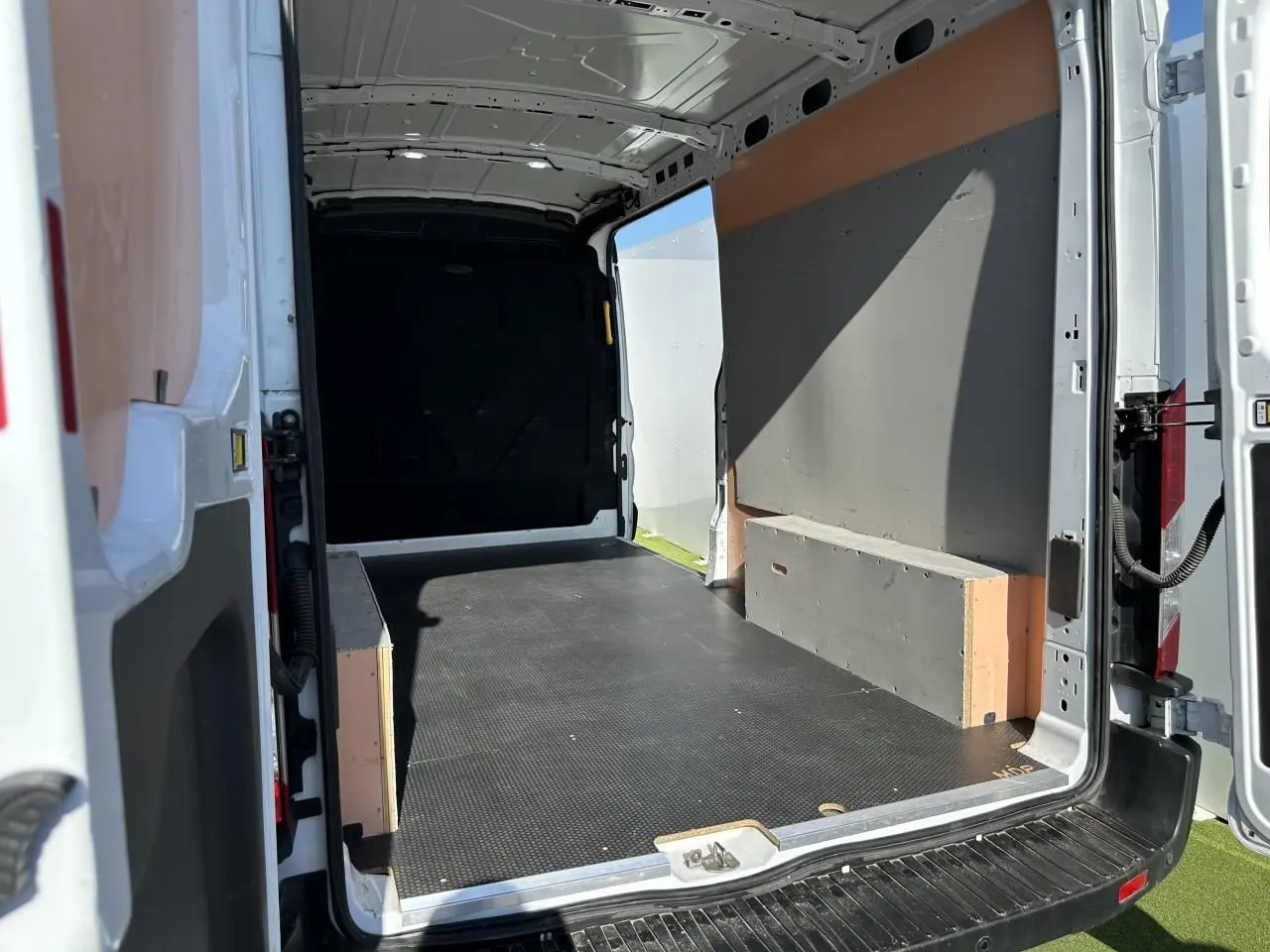 Vue intérieure arrière du fourgon blanc Ford Transit IV 2.0 EcoBlue 2020 avec espace de chargement vide et plancher noir.