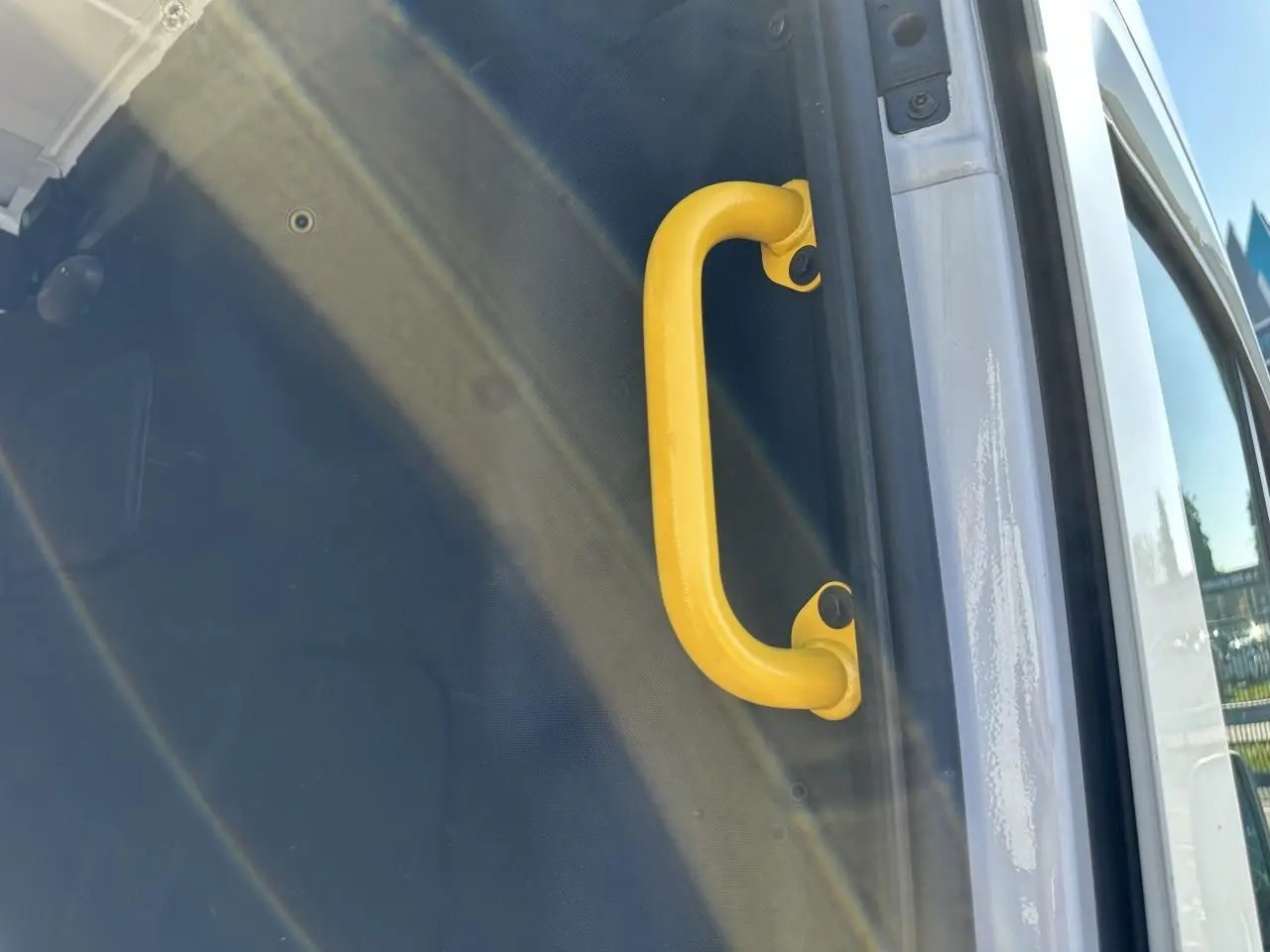 Poignée de maintien jaune visible sur l'ouverture latérale droite du fourgon blanc Ford Transit 2020.
