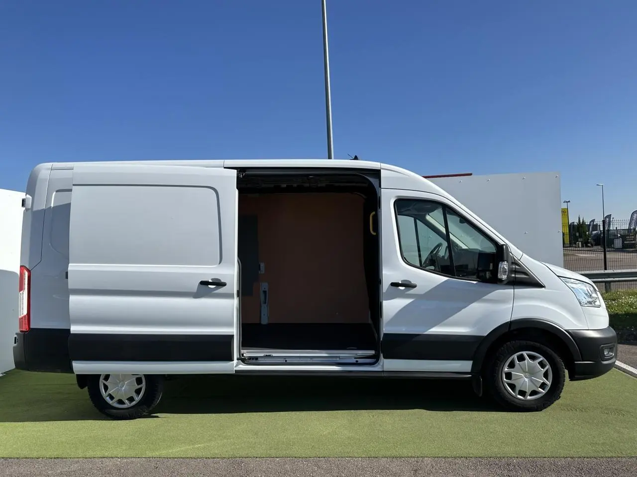 Vue latérale droite d'un Ford Transit Fourgon blanc avec porte coulissante ouverte montrant l'espace de chargement vide.