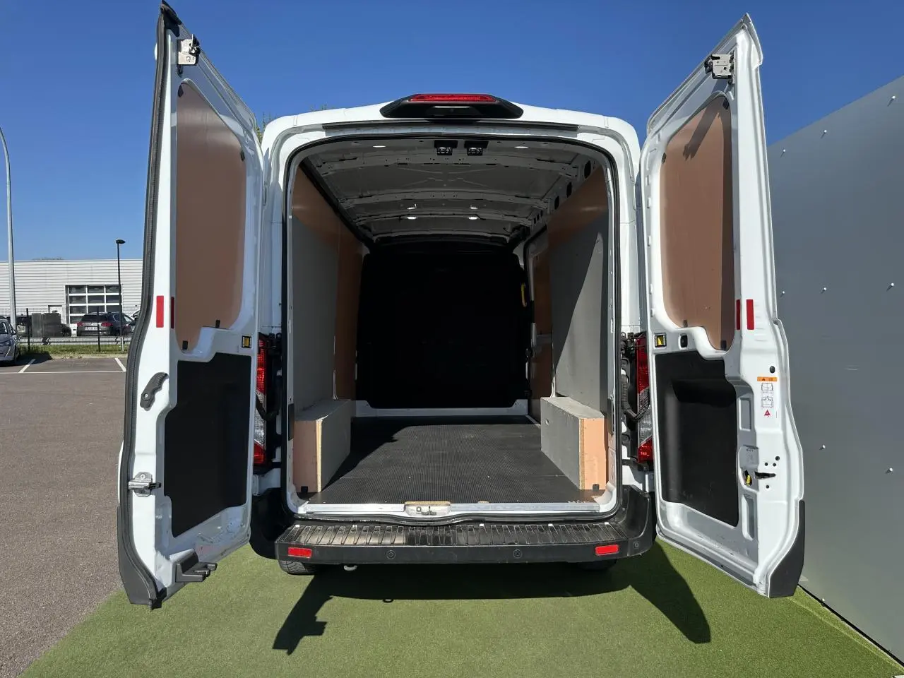 Vue arrière ouverte du Ford Transit Fourgon blanc 2020, montrant l'espace de chargement vide et les portes battantes ouvertes.