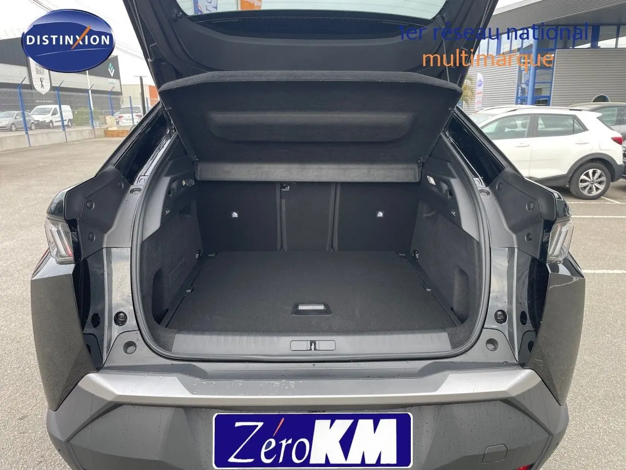 Coffre ouvert vu de l'arrière d'un Peugeot 3008 HYBRID noir perle métal, montrant un espace de chargement spacieux.