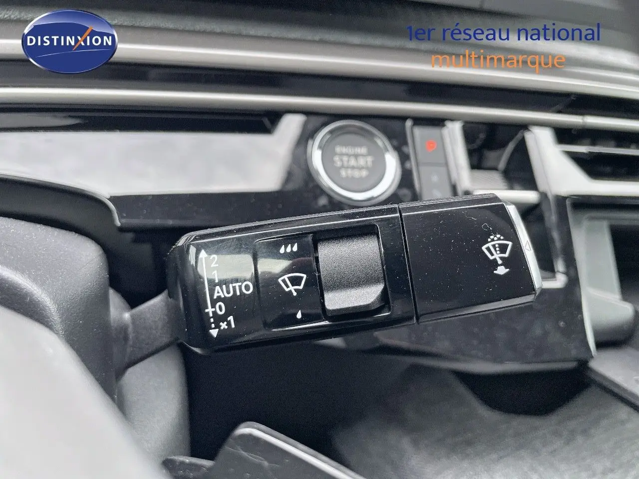 Gros plan sur la commande d'essuie-glace du Peugeot 3008 Hybrid 2025, tableau de bord noir brillant avec bouton start visible.