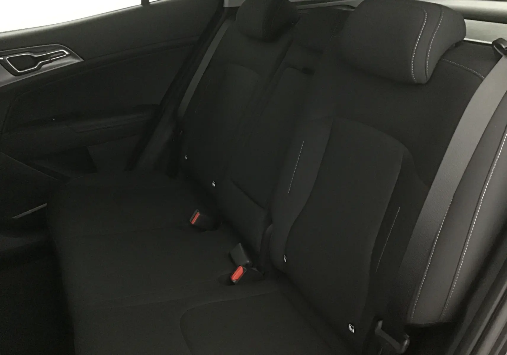 Vue intérieure du siège arrière côté gauche du Kia Sportage noir 2025, tissu sombre avec surpiqûres contrastantes.