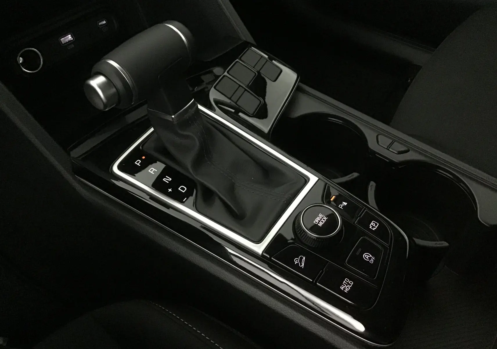 Gros plan sur la console centrale du Kia Sportage noir 2025, mettant en valeur le levier de vitesses automatique et les commandes de conduite.
