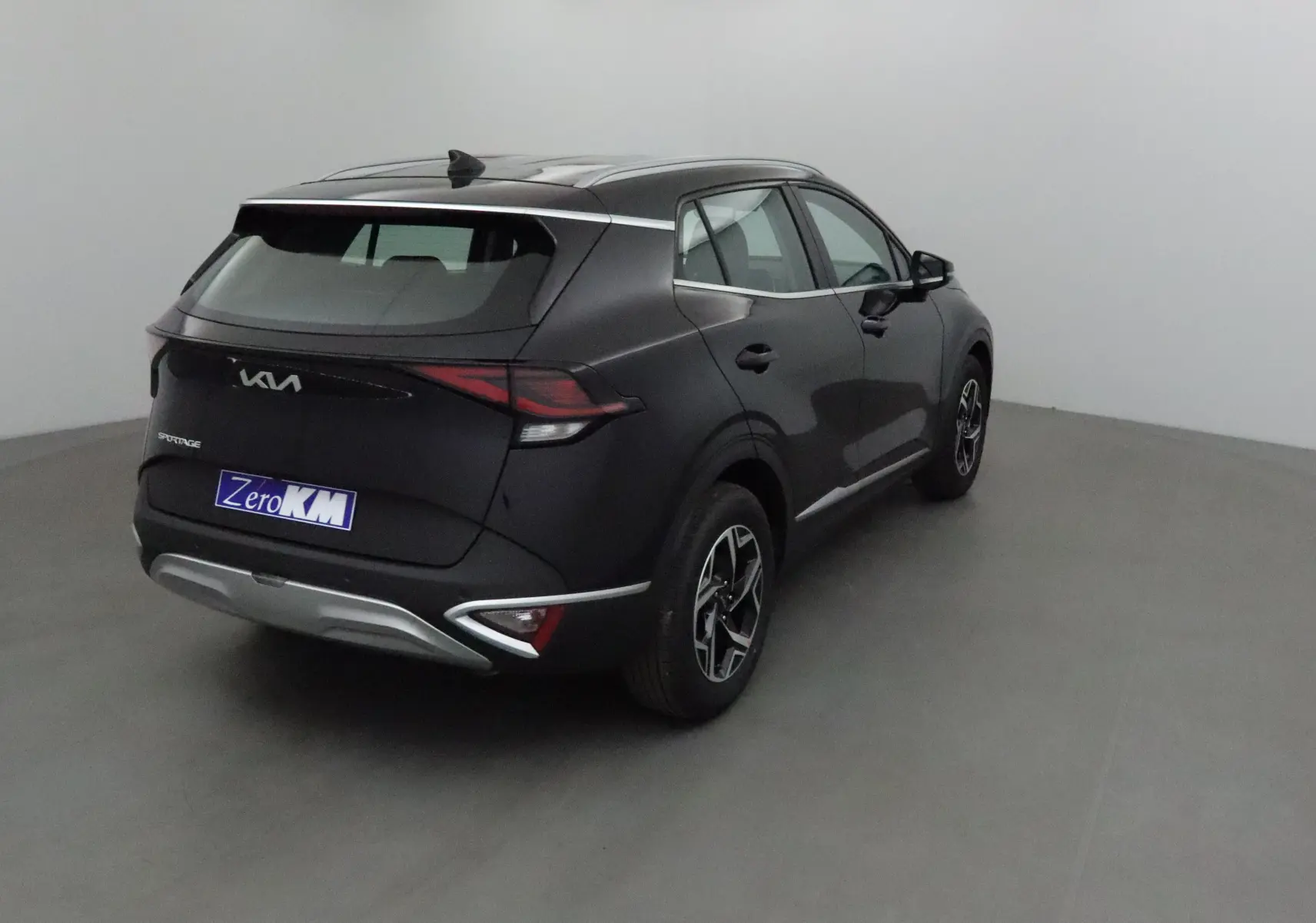 Vue 3/4 arrière droite du SUV noir KIA SPORTAGE 2025 avec feux LED et jantes alliage distinctives.