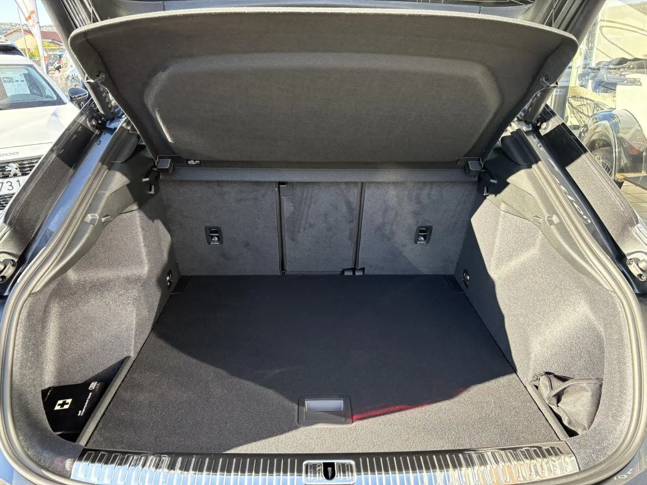 Coffre ouvert vu de l'arrière d'un Audi Q3 Sportback gris Daytona, espace de chargement propre et spacieux.