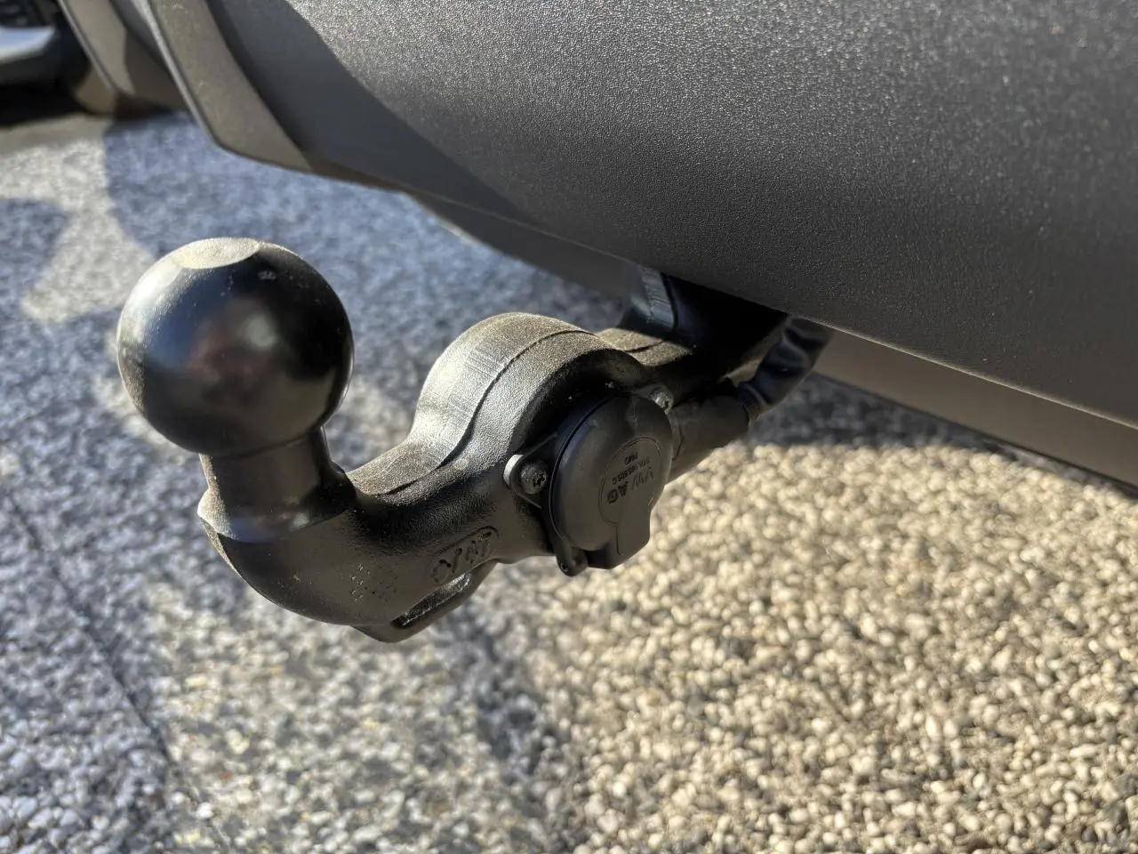 Gros plan sur le crochet d'attelage noir fixé à l'arrière d'un Audi Q3 Sportback gris Daytona.