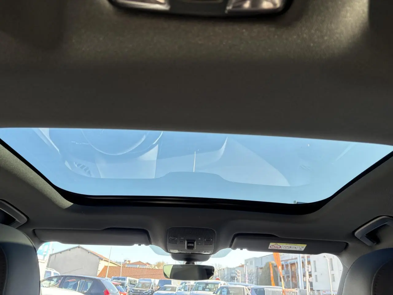 Vue intérieure du toit ouvrant panoramique du SUV Audi Q3 Sportback gris Daytona, avec ciel bleu visible à travers le verre.