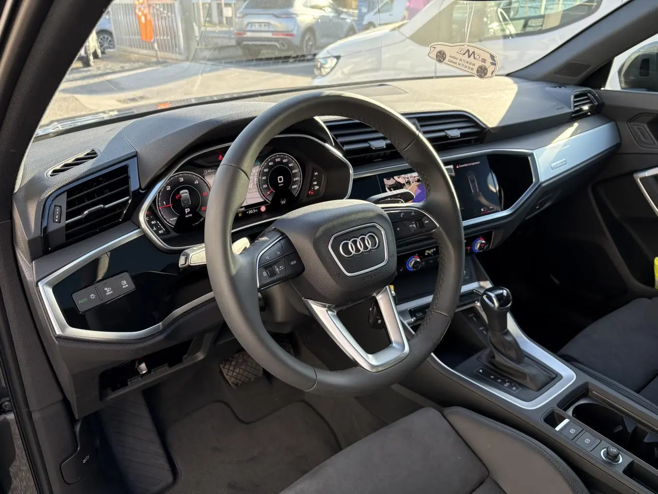 Intérieur de l'Audi Q3 Sportback 2025 vu côté conducteur, volant cuir, tableau de bord numérique et console centrale moderne.