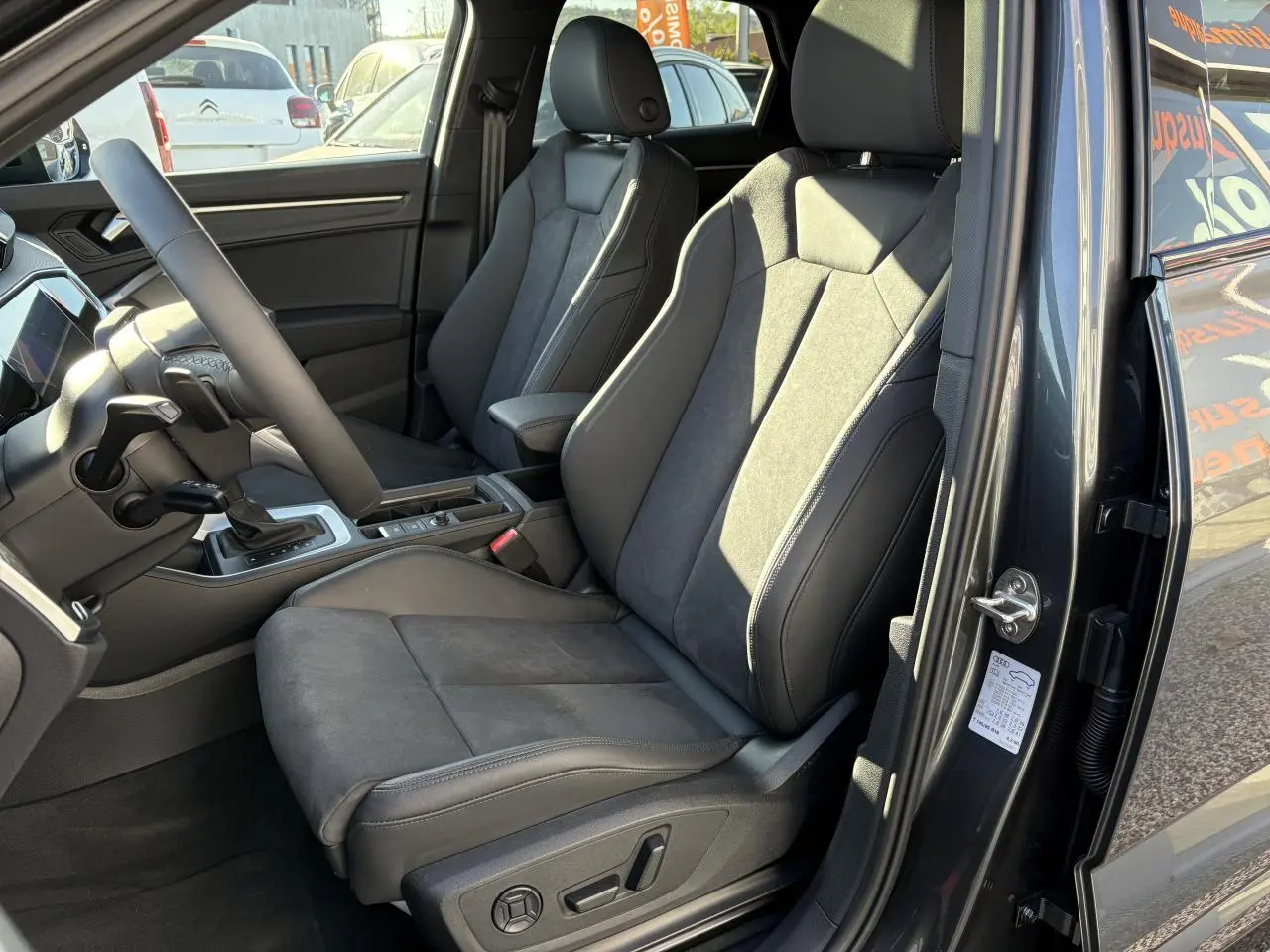 Vue intérieure côté conducteur de l'Audi Q3 Sportback gris Daytona avec sièges sport en tissu et alcantara noirs.