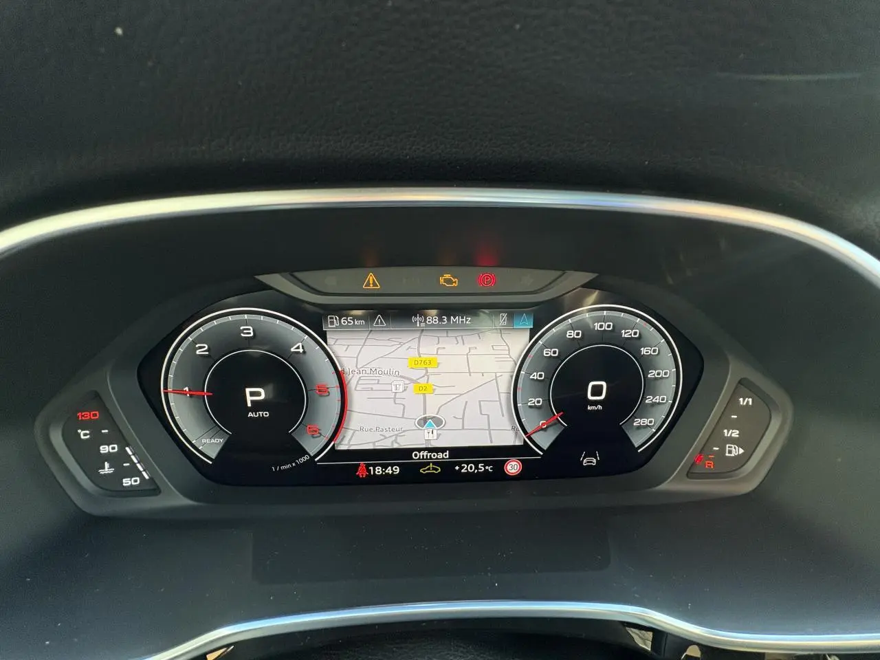 Combiné d'instruments numérique Audi virtual cockpit affichant la navigation et compteurs dans un Audi Q3 Sportback gris Daytona.