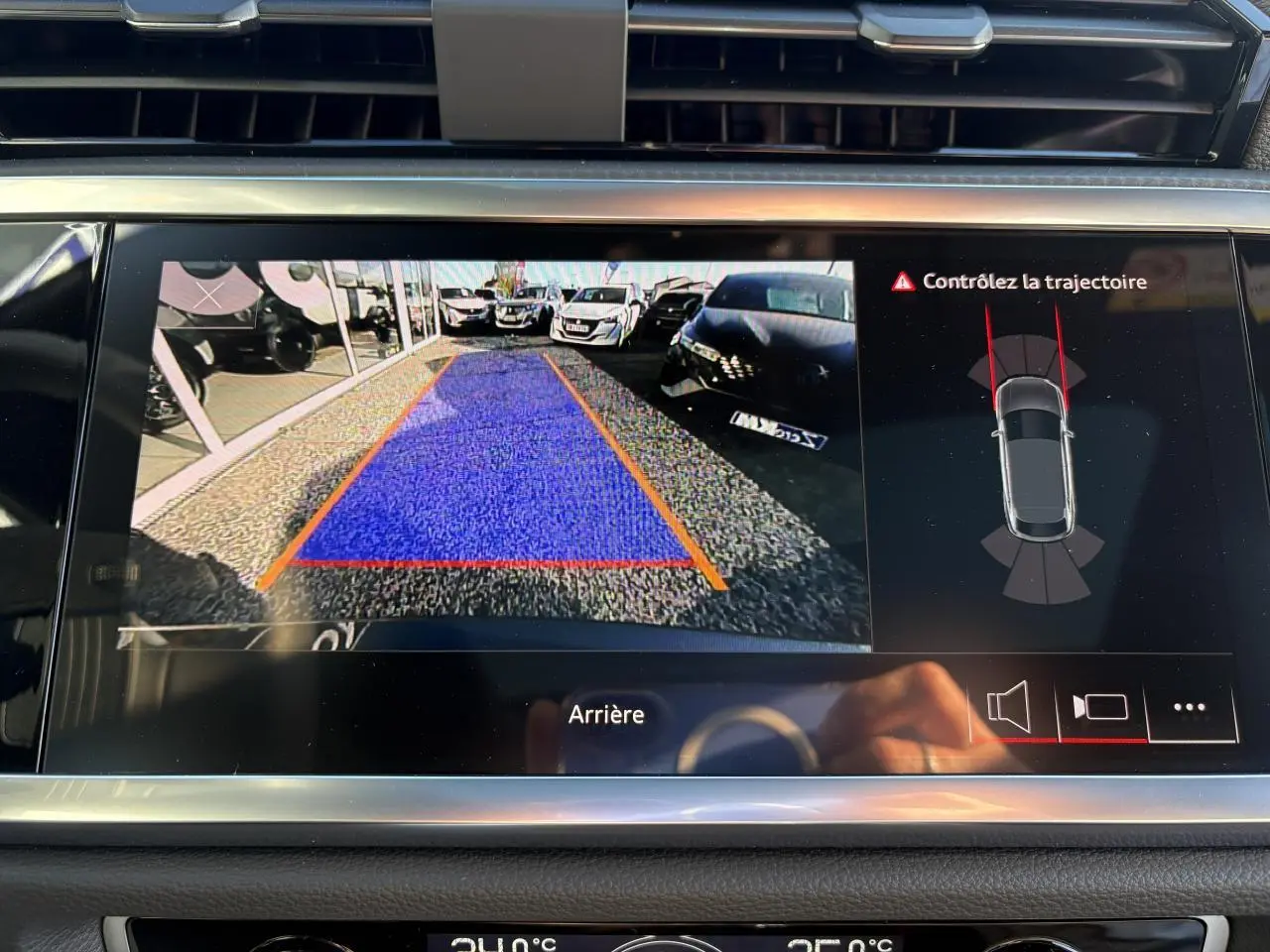 Écran de caméra de recul de l'Audi Q3 Sportback gris Daytona montrant la zone de stationnement avec alertes trajectoire.